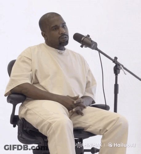 A Man Sitting In Front Of A Microphone With A Hailup Ai Logo On The Bottom Right GIF