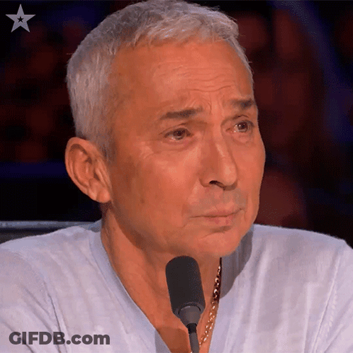 A Man Sitting In Front Of A Microphone With A Star In The Upper Right Corner GIF