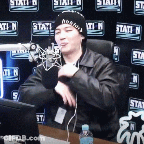 A Man Sitting In Front Of A Microphone With A Station N Wall Behind Him GIF