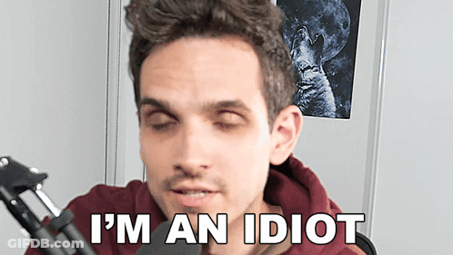 A Man Sitting In Front Of A Microphone With His Eyes Closed And The Words I 'M An Idiot Below Him GIF
