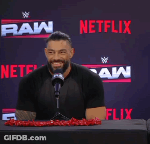 A Man Sitting In Front Of A Microphone With Netflix In The Background GIF
