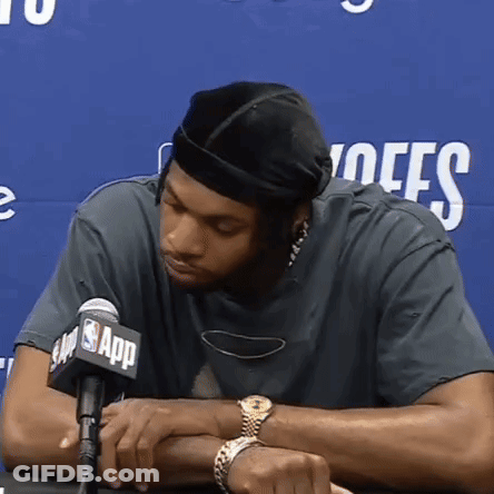 A Man Sitting In Front Of A Microphone With The Nba App Logo On It GIF