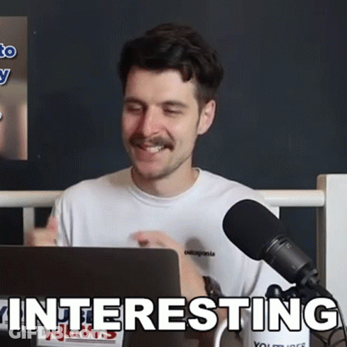 A Man Sitting In Front Of A Microphone With The Word Interesting Written On The Bottom GIF