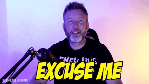 A Man Sitting In Front Of A Microphone With The Words " Excuse Me " On His Shirt GIF