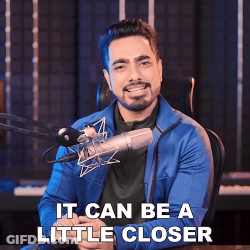 A Man Sitting In Front Of A Microphone With The Words It Can Be A Little Closer GIF