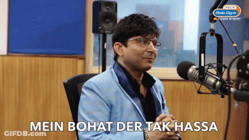 A Man Sitting In Front Of A Microphone With The Words Mein Bohat Der Tak Hassa Written Below Him GIF