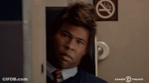 A Man Sitting In Front Of A No Smoking Sign From Comedy Central GIF