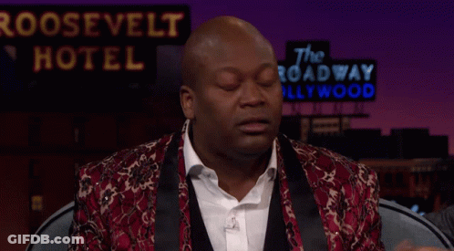 A Man Sitting In Front Of A Roosevelt Hotel Sign With His Hands In The Air GIF