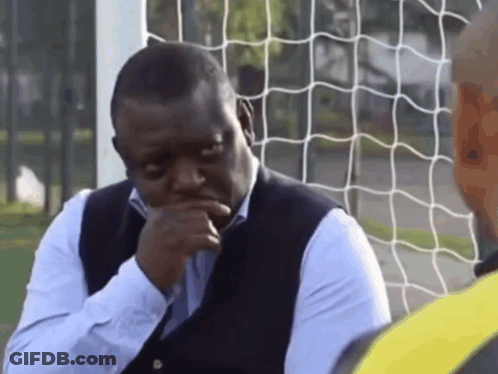 A Man Sitting In Front Of A Soccer Net With His Hand To His Chin GIF