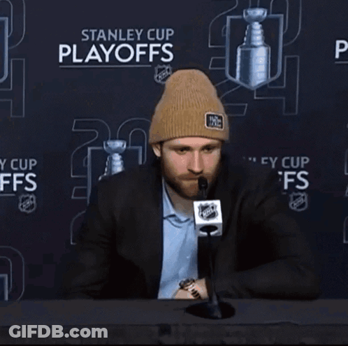 A Man Sitting In Front Of A Stanley Cup Playoffs Advertisement GIF