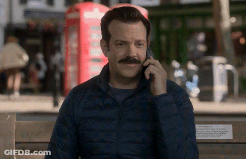 A Man Sitting On A Bench Talking On A Cell Phone GIF