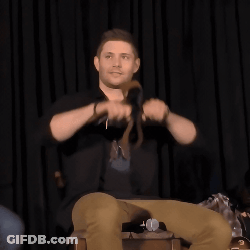 A Man Sitting On A Chair Holding A Microphone GIF