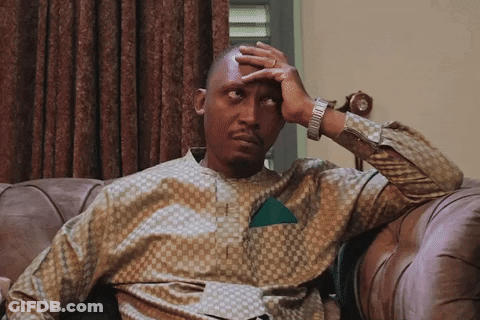 A Man Sitting On A Couch Covering His Face With His Hand GIF