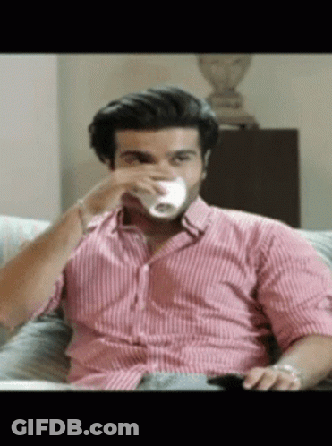 A Man Sitting On A Couch Drinking From A Cup GIF