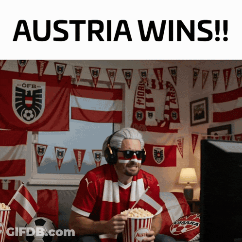 A Man Sitting On A Couch Holding A Popcorn Bucket That Says Austria Wins GIF