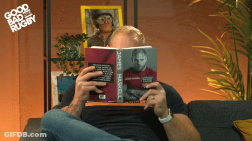 A Man Sitting On A Couch Reading A Book Called James Haskell GIF