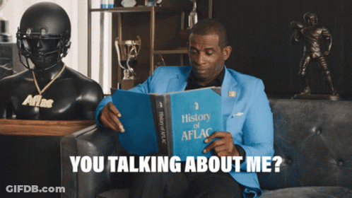 A Man Sitting On A Couch Reading A Book Titled History Of Aflg GIF