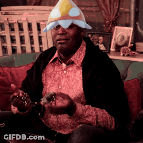 A Man Sitting On A Couch Wearing A Flower Hat GIF