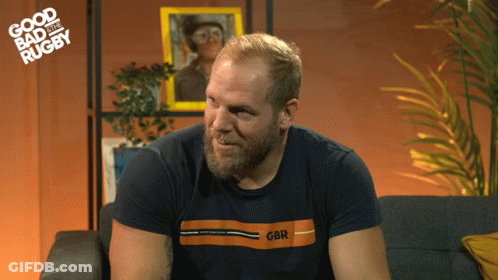 A Man Sitting On A Couch Wearing A Gbr Shirt GIF