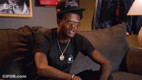 A Man Sitting On A Couch Wearing A Hat That Says ' Ford ' On It GIF