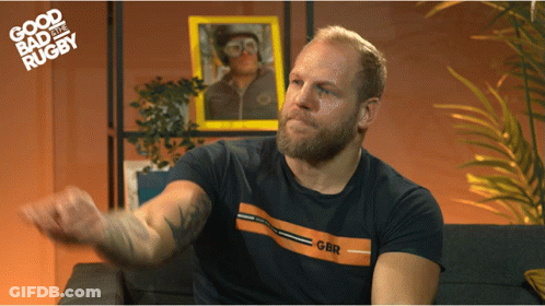 A Man Sitting On A Couch Wearing A Shirt That Says Gbr On It GIF
