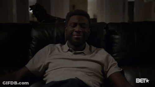 A Man Sitting On A Couch With A Bet Logo On The Bottom GIF