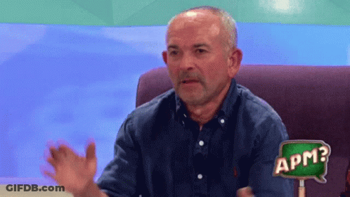 A Man Sitting On A Couch With A Sign That Says Apm GIF