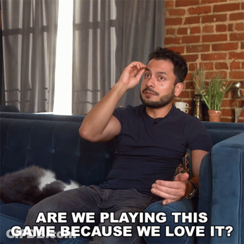A Man Sitting On A Couch With The Words Are We Playing This Game Because We Love It Below Him GIF