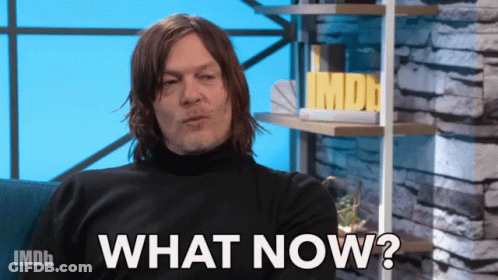 A Man Sitting On A Couch With The Words " What Now " On The Screen GIF