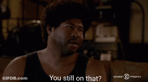 A Man Sitting On A Couch With The Words " You Still On That " In Front Of Him GIF