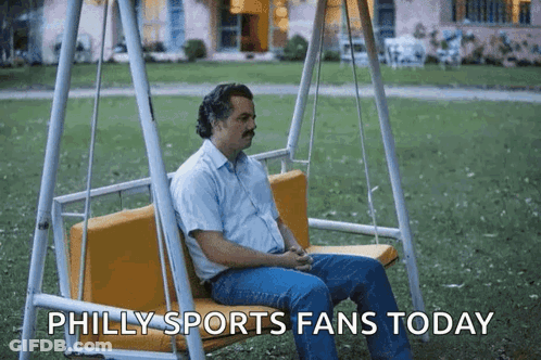 A Man Sitting On A Swing With The Words Philly Sports Fans Today GIF