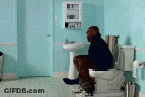 A Man Sitting On A Toilet In A Bathroom GIF
