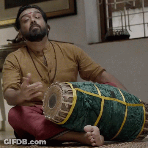 A Man Sitting On The Floor Playing A Drum GIF