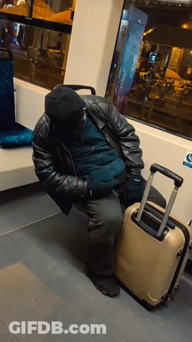 A Man Sleeping On A Bus Next To A Suitcase With A Sticker On The Wall That Says ' Handicap ' GIF