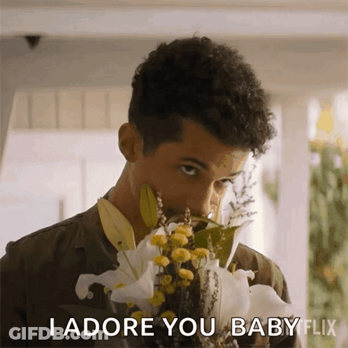 A Man Smelling A Bouquet Of Flowers With The Words I Adore You Baby Flix Below Him GIF