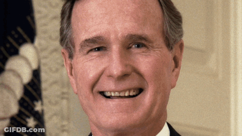 A Man Smiles In Front Of A Flag That Says United States Of America GIF