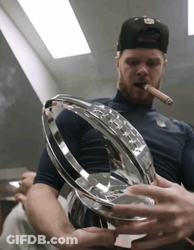 A Man Smoking A Cigar While Holding A Trophy In His Hands GIF