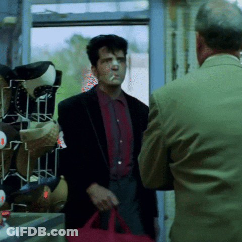 A Man Smoking A Cigarette And Holding A Red Bag GIF