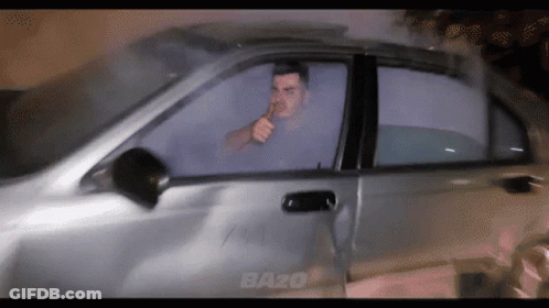 A Man Smoking A Cigarette In A Car With The Word Bazo On The Side GIF
