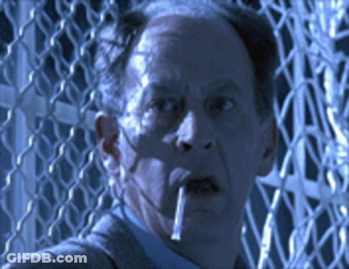 A Man Smoking A Cigarette In Front Of A Wire Fence GIF