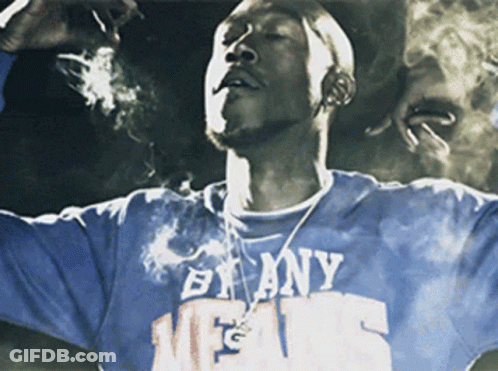 A Man Smoking A Cigarette Wearing A Shirt That Says By Any Means GIF