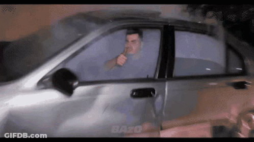 A Man Smoking A Cigarette While Driving A Car With The Word Bazo On The Bottom GIF