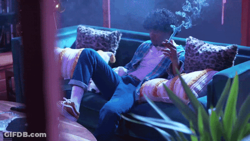 A Man Smoking A Cigarette While Laying On A Couch GIF