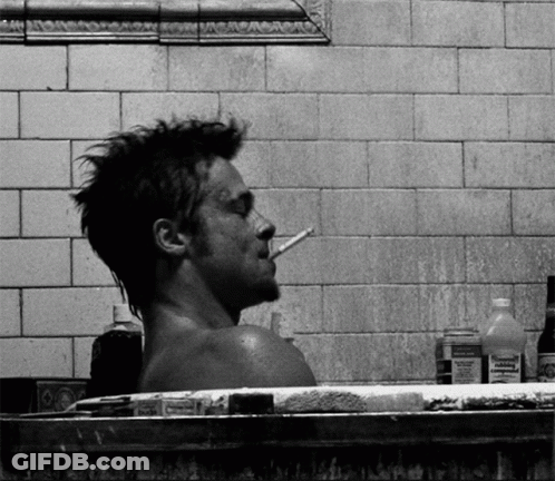 A Man Smoking A Cigarette While Taking A Bath In A Bathtub Surrounded By Bottles Of Medicine GIF