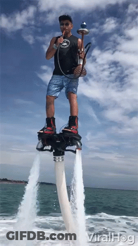 A Man Smoking A Hookah While Standing On A Water Jet Board GIF