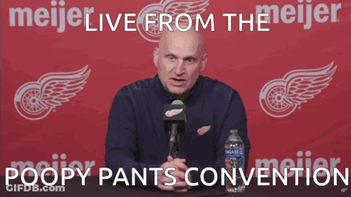 A Man Speaking Into A Microphone In Front Of A Meijer Logo GIF
