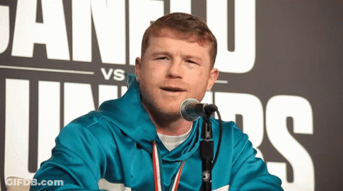 A Man Speaking Into A Microphone In Front Of A Sign That Says Juan U Vs Juniors GIF