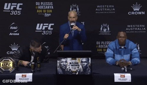A Man Speaking Into A Microphone In Front Of A Ufc 305 Banner GIF