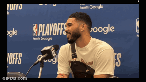 A Man Speaking Into A Microphone In Front Of A Wall That Says Playoffs On It GIF