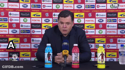 A Man Speaking Into A Microphone In Front Of A Wall With Fox Logos On It GIF